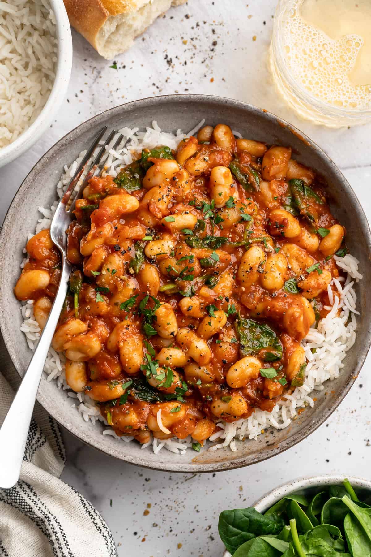 These 30-minute smoky white beans in tomato sauce are made with liquid smoke and plenty of garlic. They're amazing on toast for breakfast! Overhead image of smoky white beans in tomato sauce served over white rice.