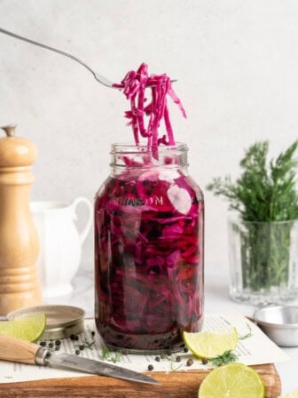 A fork lifting some pickled red cabbage from a jar.