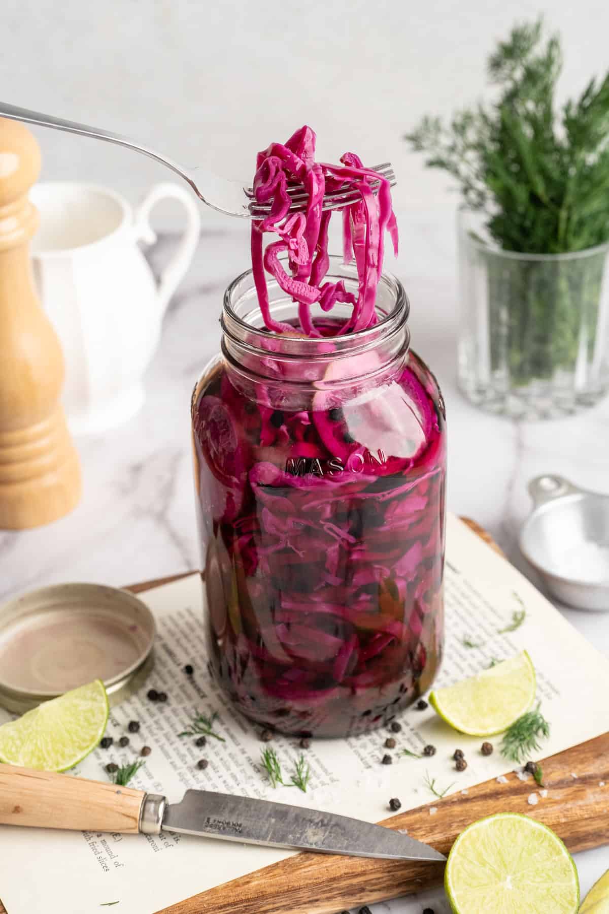 This quick pickled cabbage comes out incredibly flavourful (brine-y, tangy, and a tad sweet) with a subtle crunch. And in just a few minutes! A fork lifting some quick pickled cabbage from a mason jar.