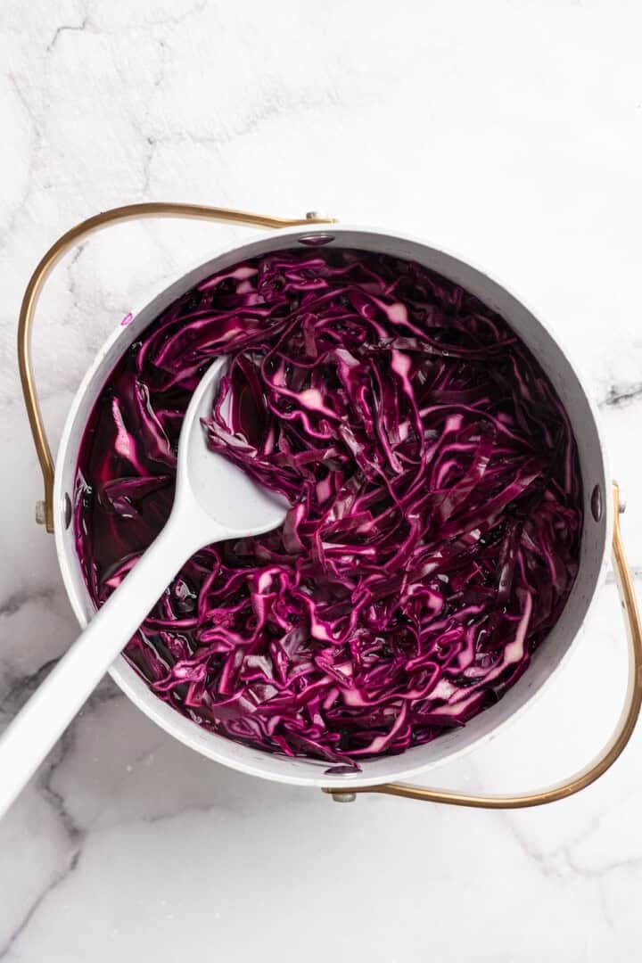 Chopped red cabbage in a pot, softened by boiling pickling liquid.