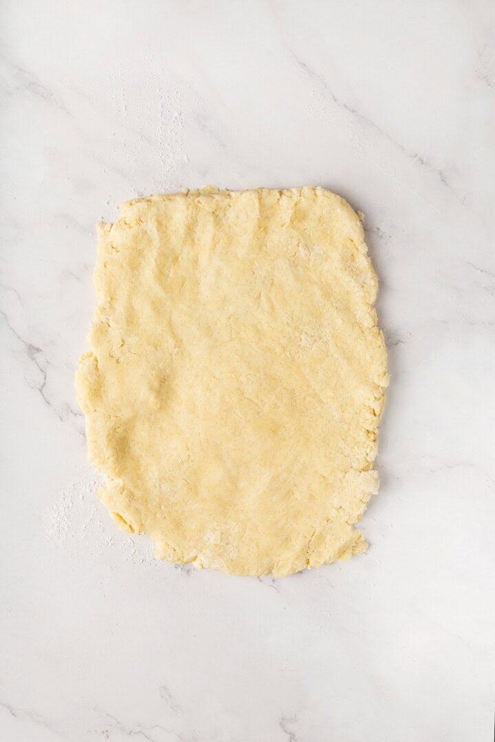 Strawberry shortcake recipe sandwiches sweet, syrupy macerated strawberries and fluffy vegan whipped cream between flaky homemade biscuits. Vegan biscuit dough shaped into a rectangle.
