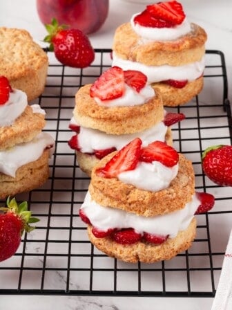 Vegan strawberry shortcakes arranged on a wire rack with a few fresh berries.