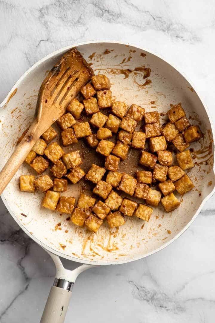 This 35-minute tempeh stir fry combines crispy golden tempeh, tender veggies, and a creamy, savoury-sweet Thai-style peanut sauce. Crispy, saucy tempeh in a pan.