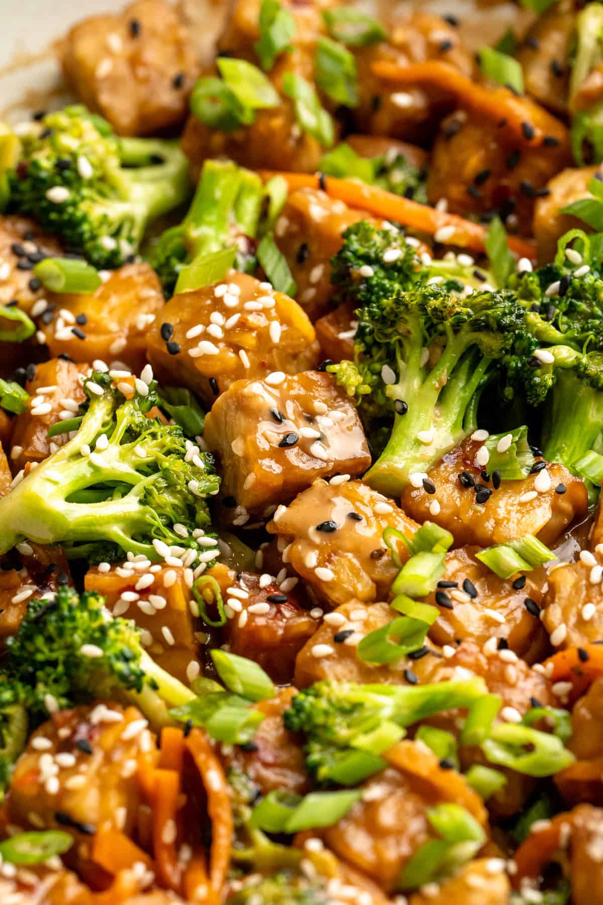 This 35-minute tempeh stir fry combines crispy golden tempeh, tender veggies, and a creamy, savoury-sweet Thai-style peanut sauce. Close-up image of tempeh stir fry.