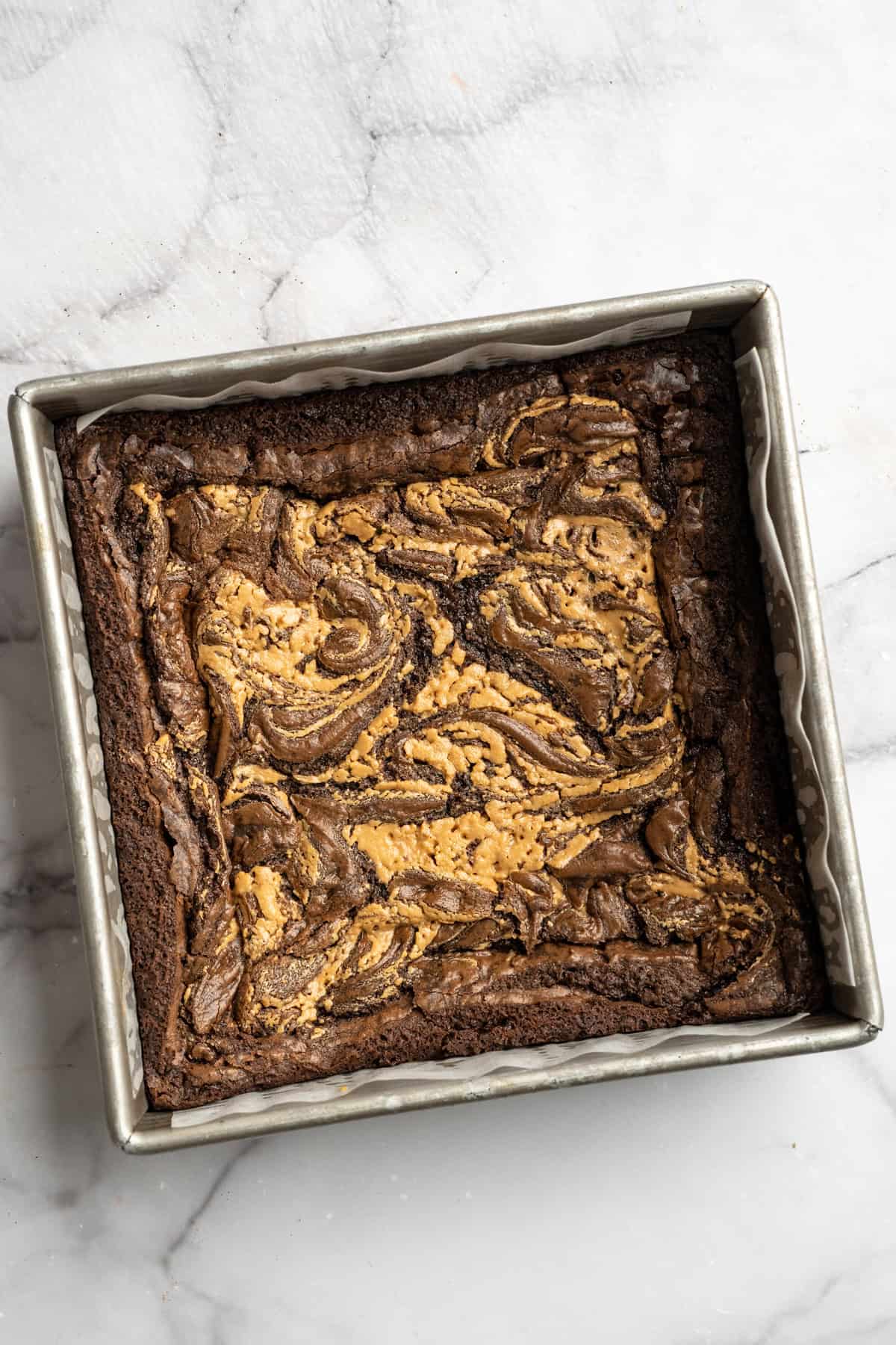 Peanut butter swirl brownies are wonderfully fudge-y, perfectly chewy, and complete with a salty ribbon of peanut butter swirled throughout. Vegan peanut butter brownies cooling in the pan.
