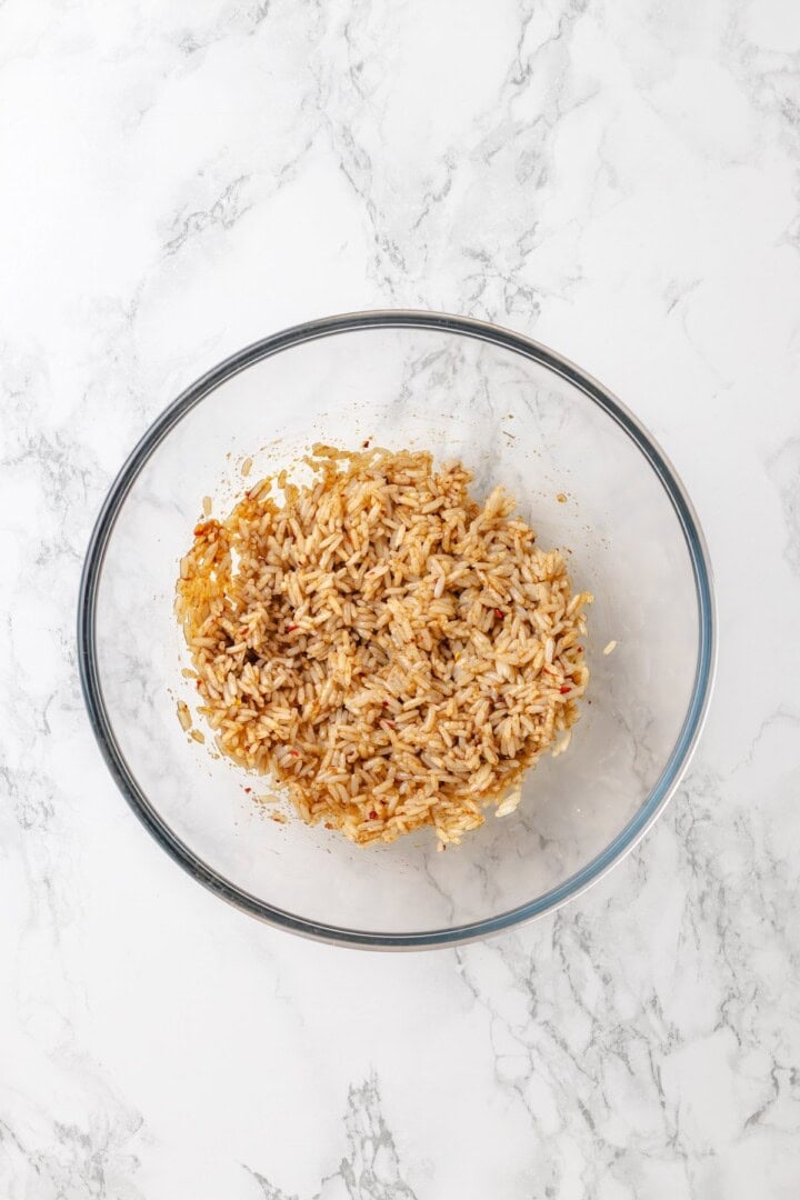 This crispy rice salad is made with soy-infused baked rice tossed with crunchy veggies, caramelized roasted tofu, and Thai peanut sauce. Day-old rice in a bowl tossed with sesame oil, soy sauce, chili flakes, and garlic powder.