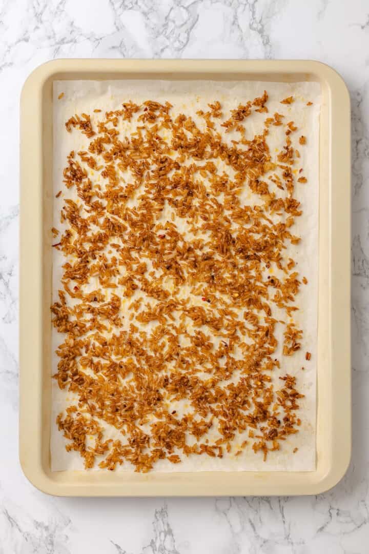 This crispy rice salad is made with soy-infused baked rice tossed with crunchy veggies, caramelized roasted tofu, and Thai peanut sauce. Crispy rice fresh out of the oven.
