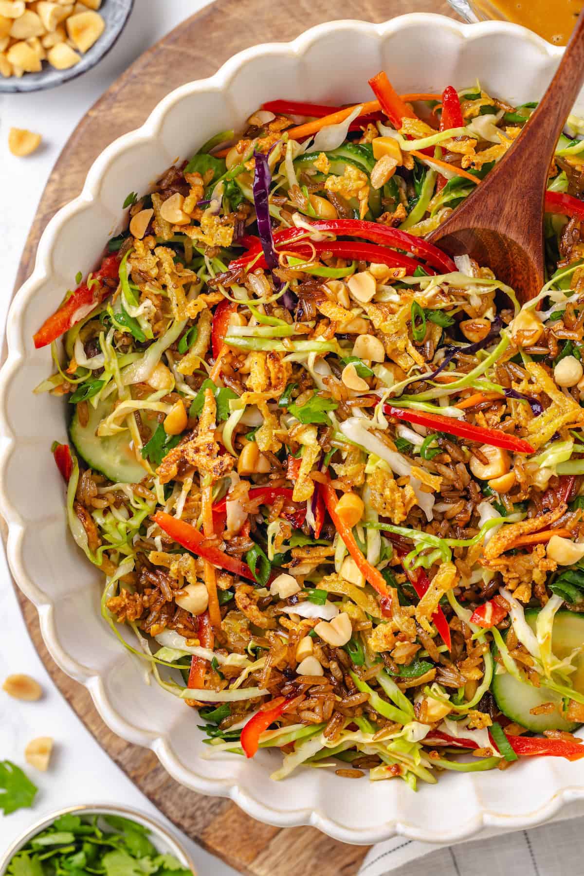 This crispy rice salad is made with soy-infused baked rice tossed with crunchy veggies, caramelized roasted tofu, and Thai peanut sauce. Overhead image of a serving bowl of crispy rice and tofu salad with peanut sauce.