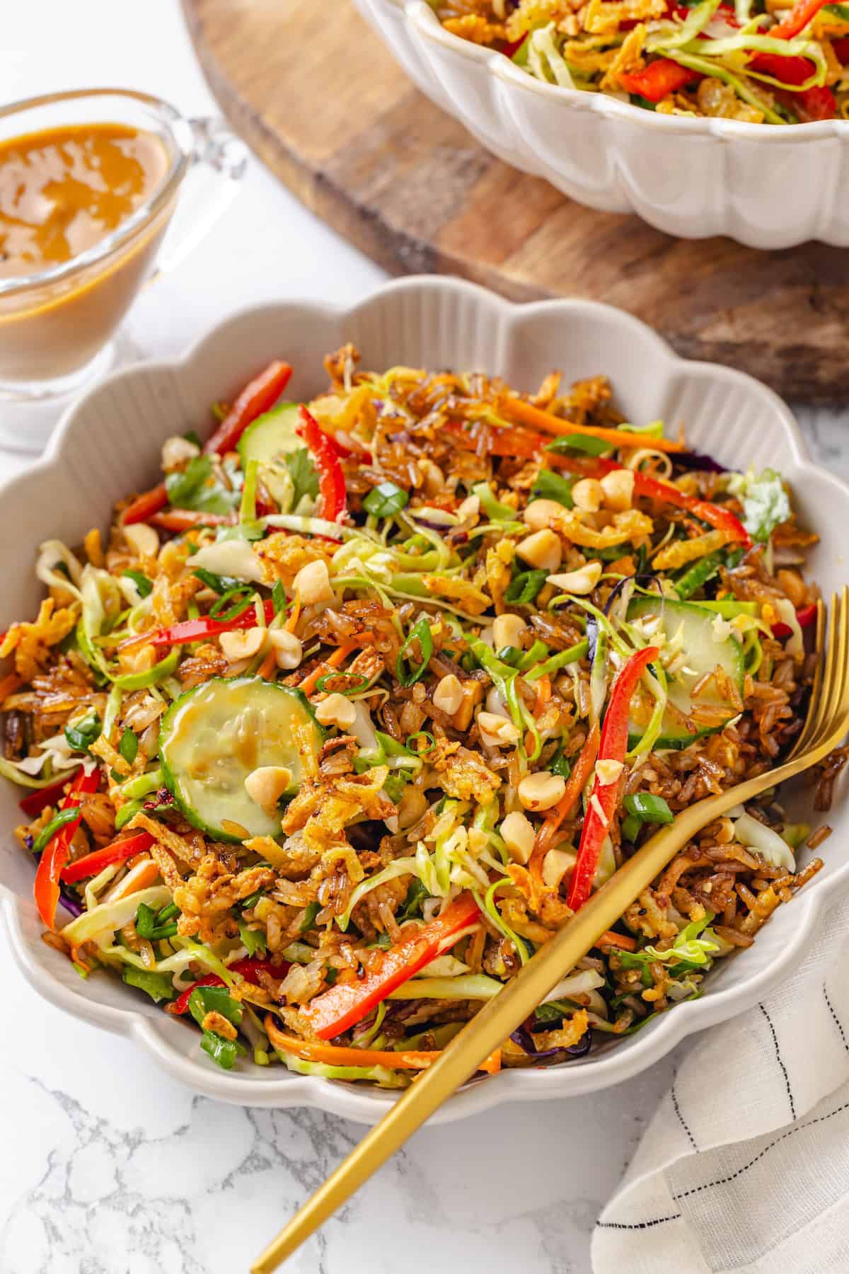 This crispy rice salad is made with soy-infused baked rice tossed with crunchy veggies, caramelized roasted tofu, and Thai peanut sauce. A bowl of crispy rice and tofu salad.