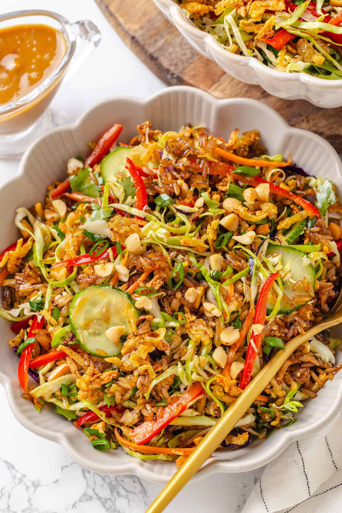 This crispy rice salad is made with soy-infused baked rice tossed with crunchy veggies, caramelized roasted tofu, and Thai peanut sauce. A bowl full of crispy rice salad.
