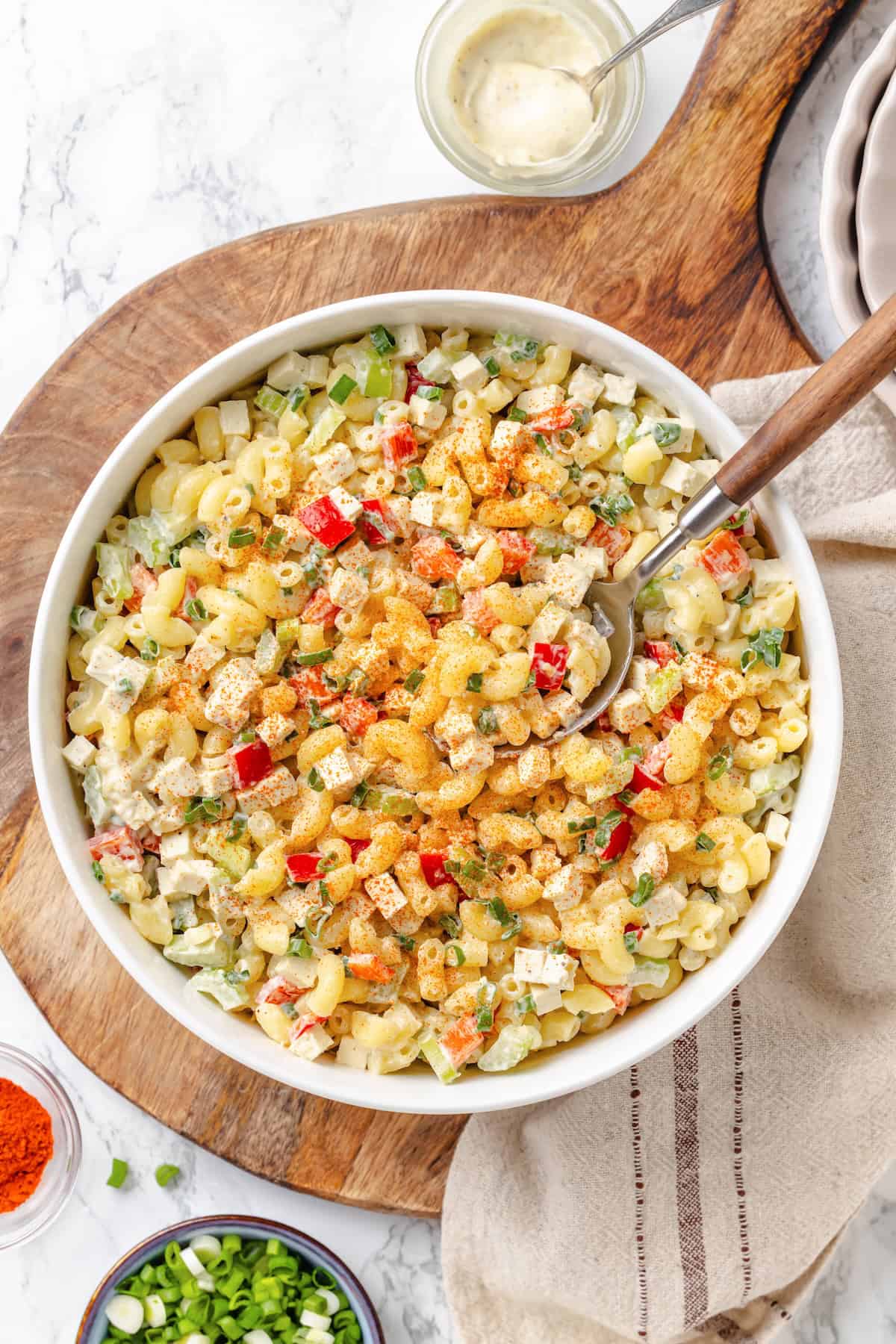 Creamy and crunchy, this macaroni salad recipe is made with crumbled tofu and a touch of kala namak for that old-school eggy flavor. Overhead image of a serving bowl loaded with vegan macaroni salad.