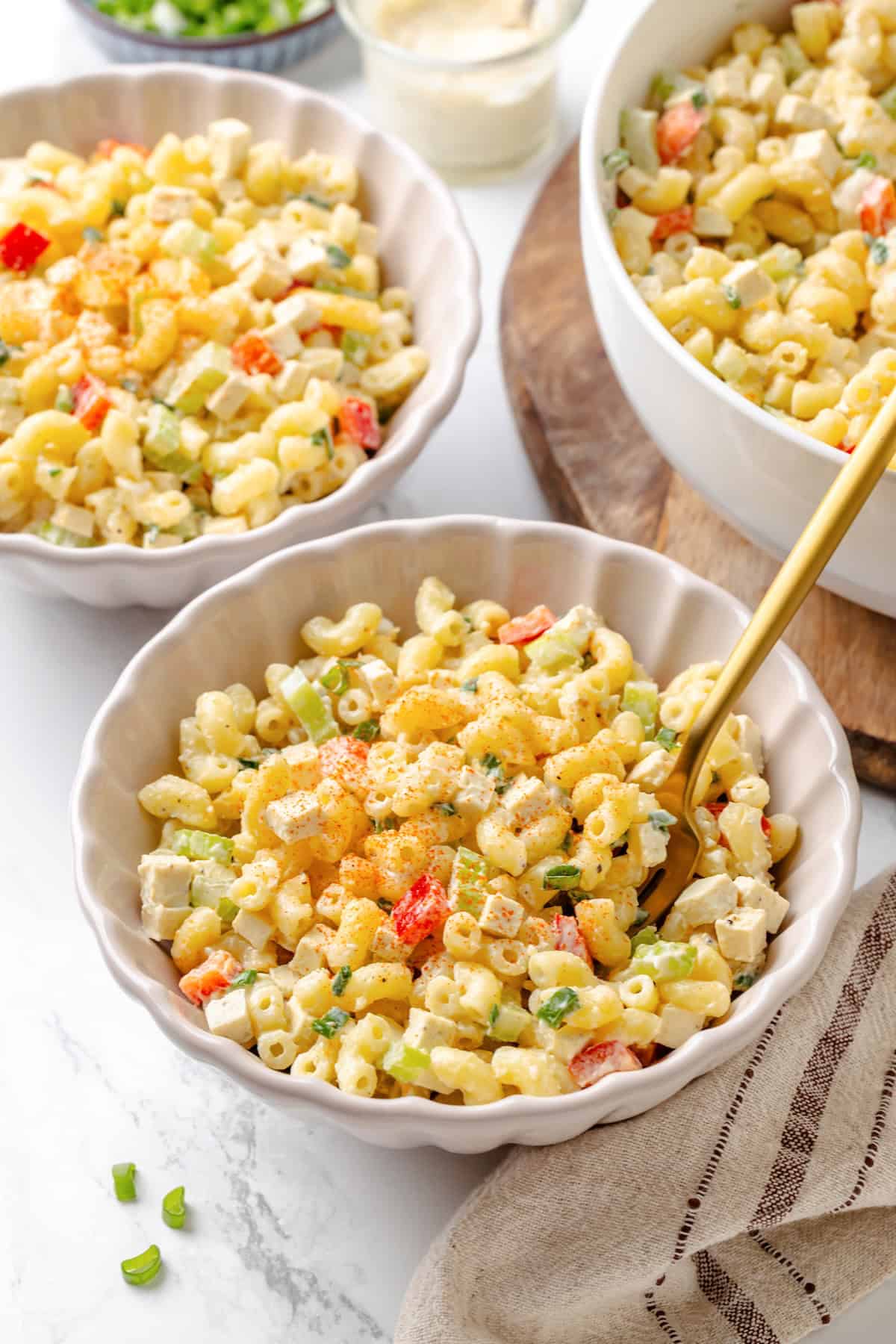 Creamy and crunchy, this macaroni salad recipe is made with crumbled tofu and a touch of kala namak for that old-school eggy flavor. A bowl of vegan mac salad with a fork.