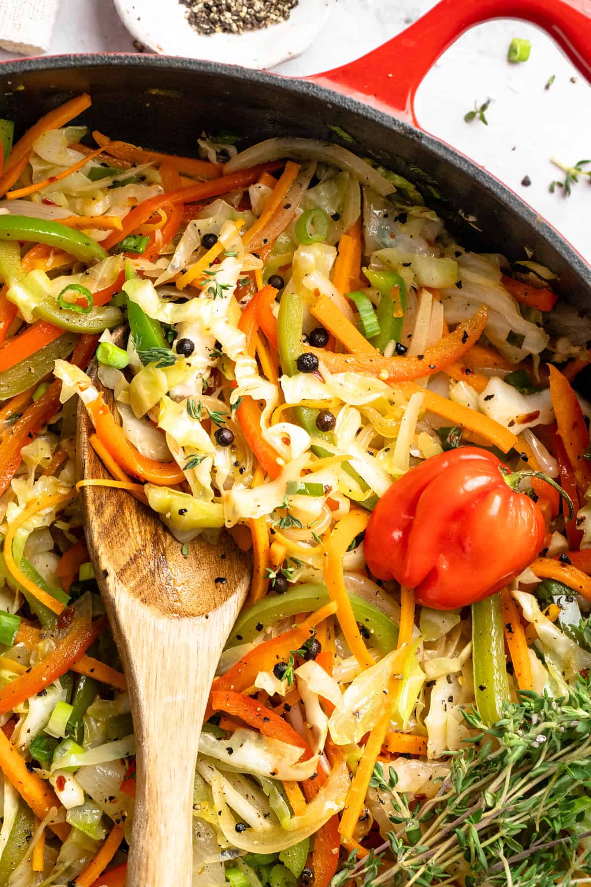 This Jamaican steamed cabbage recipe uses simple cooking methods and simple ingredients to infuse veggies with sweet, savoury island flavour. Close-up of Jamaican steamed cabbage in a Dutch oven.