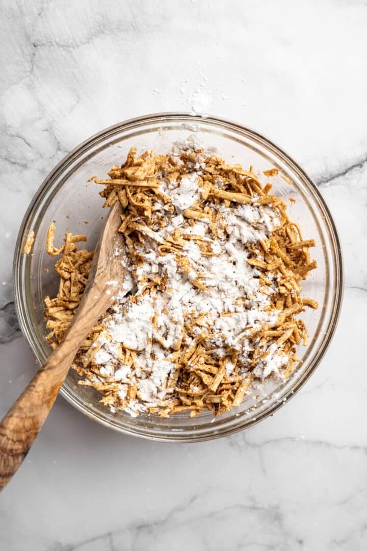 This shredded tofu is tossed in a savoury sauce and baked to crispy golden brown. It's the perfect protein addition to any vegan meal. Adding cornstarch to saucy shredded tofu.