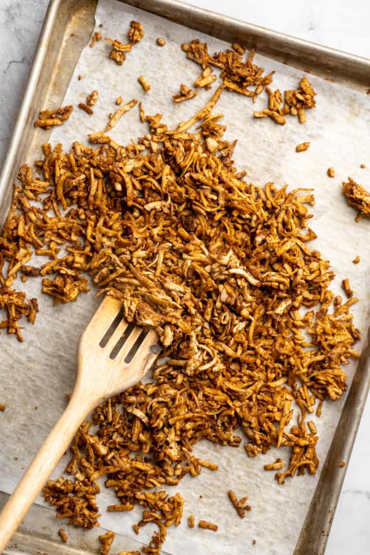 This shredded tofu is tossed in a savoury sauce and baked to crispy golden brown. It's the perfect protein addition to any vegan meal. Tossing shredded tofu 8 minutes into baking.