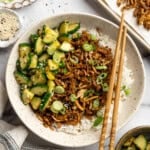 A bowl of shredded tofu served over rice with Asian cucumber salad.