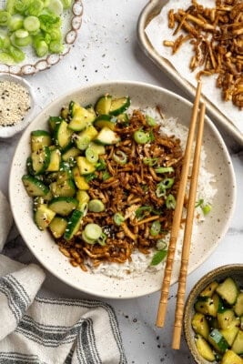 A bowl of shredded tofu served over rice with Asian cucumber salad.