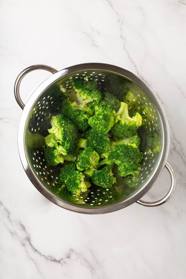 Cheesy vegan smashed broccoli is the perfect way to mix up your veggie routine. Served with a creamy garlic sauce, it's sure to impress. Draining boiled broccoli florets.