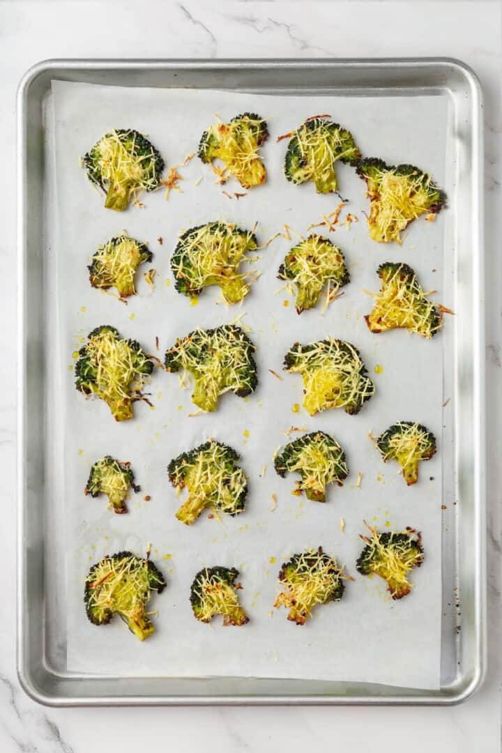 Cheesy vegan smashed broccoli is the perfect way to mix up your veggie routine. Served with a creamy garlic sauce, it's sure to impress. Baked, cheesy smashed broccoli florets on a sheet pan/