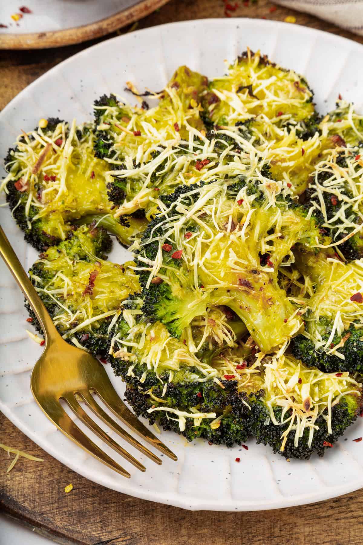 Cheesy vegan smashed broccoli is the perfect way to mix up your veggie routine. Served with a creamy garlic sauce, it's sure to impress. A plate of smashed broccoli.