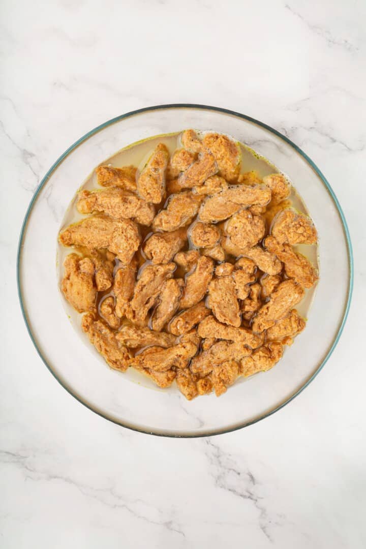 These vegan soy curl tacos pair perfectly crispy soy curl "chicken" with classic taco toppings and the BEST tangy, creamy lime sauce. Soy curls soaking in hot broth.