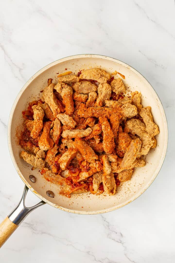 These vegan soy curl tacos pair perfectly crispy soy curl "chicken" with classic taco toppings and the BEST tangy, creamy lime sauce. Adding seasoned soy curls to a pan with sautéed tomato paste, garlic, and onion.