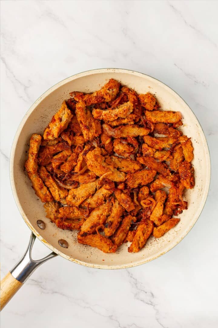 These vegan soy curl tacos pair perfectly crispy soy curl "chicken" with classic taco toppings and the BEST tangy, creamy lime sauce. Crispy seasoned soy curls in a pan, ready to make tacos.