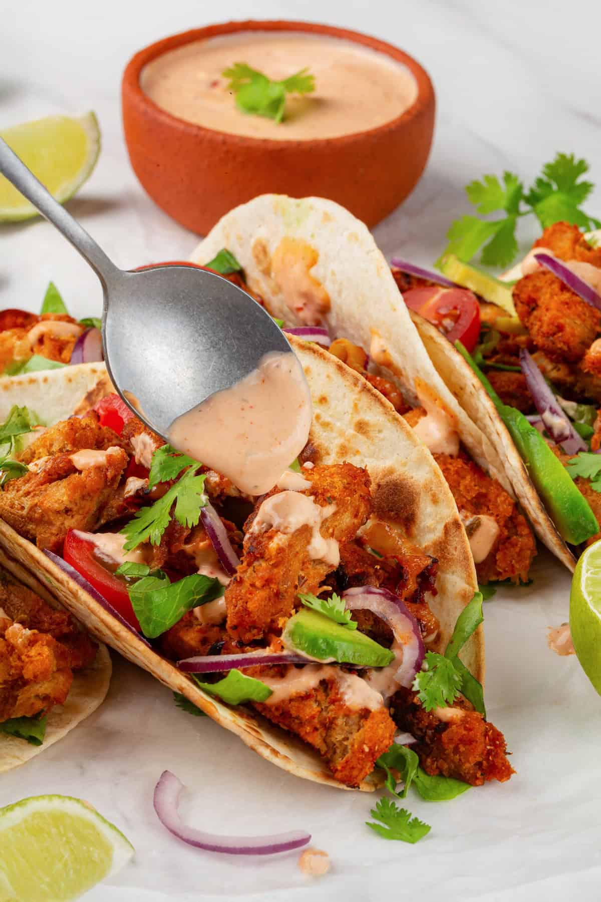 These vegan soy curl tacos pair perfectly crispy soy curl "chicken" with classic taco toppings and the BEST tangy, creamy lime sauce. Drizzling lime taco sauce over soy curl tacos.