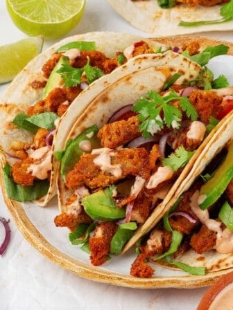 Close-up of three soy curl tacos on a plate.