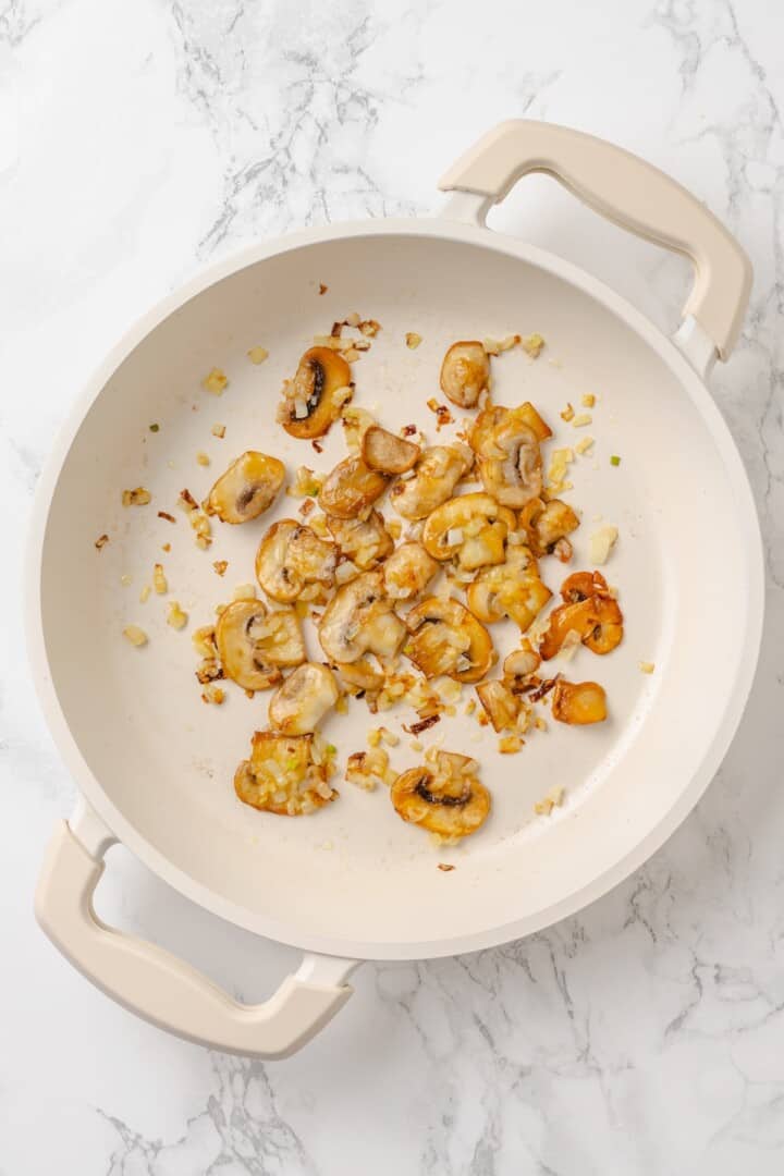 Start today right with this vegan omelette! Chickpea flour and water combine to make a tender omelette filled with veggies and vegan cheese. Sautéing shallot and mushrooms in a pan.
