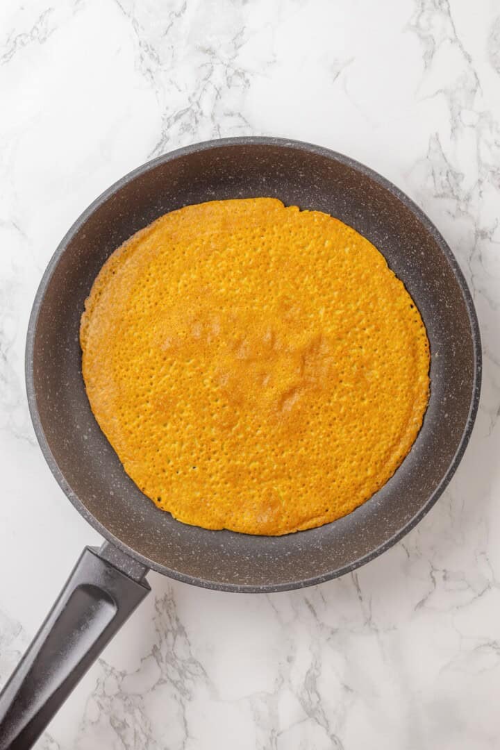 Start today right with this vegan omelette! Chickpea flour and water combine to make a tender omelette filled with veggies and vegan cheese. An omelette made with chickpea flour, flipped in a skillet.