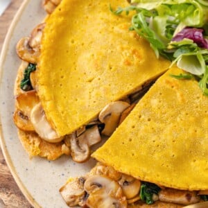 A vegan chickpea flour omelette cut in half on a plate.