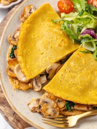 A vegan chickpea flour omelette cut in half on a plate.