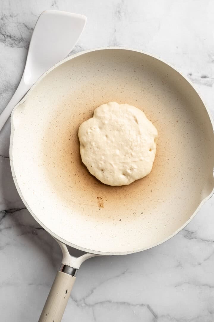Easy to make and SO light and fluffy, these vegan cottage cheese pancakes are about to become your go-to, protein-packed breakfast. Cooking a vegan cottage cheese pancake in a skillet (before flipping).