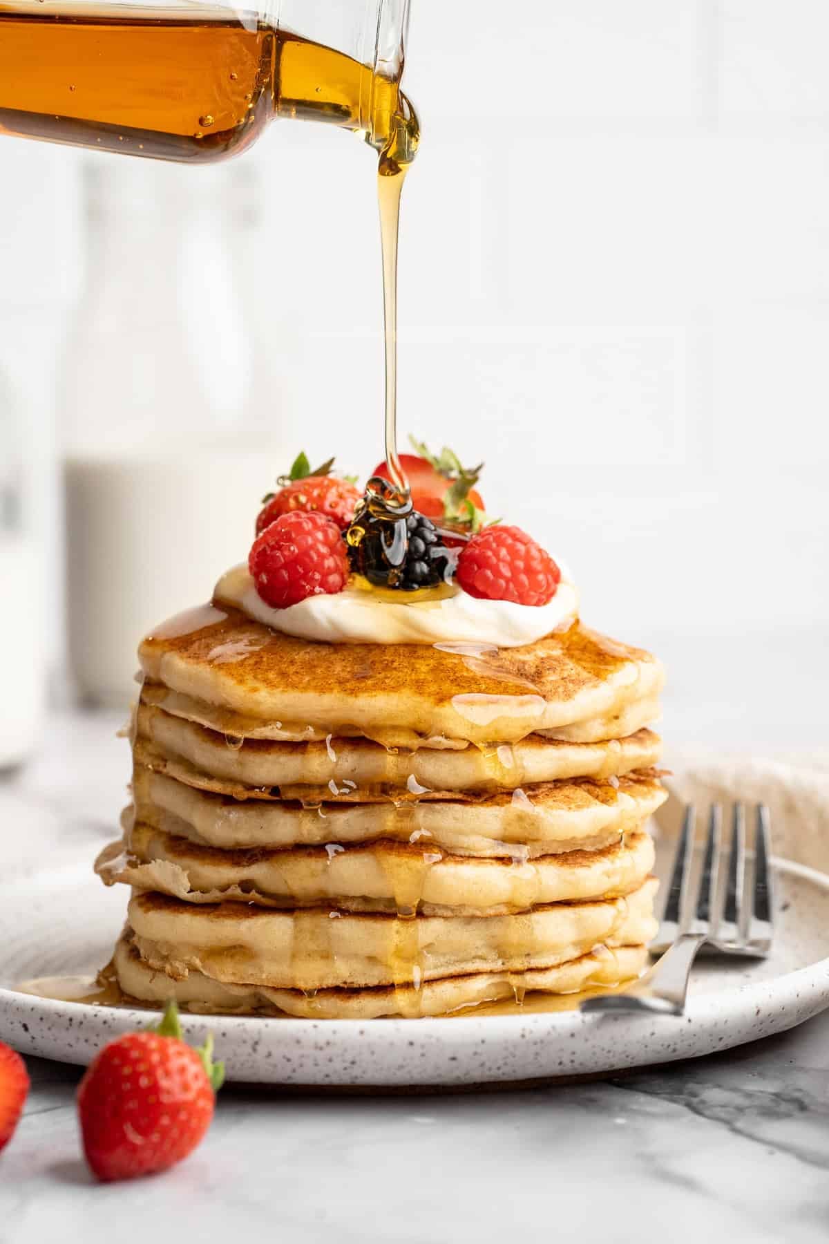 Easy to make and SO light and fluffy, these vegan cottage cheese pancakes are about to become your go-to, protein-packed breakfast. Pouring maple syrup over a stack of vegan cottage cheese pancakes.