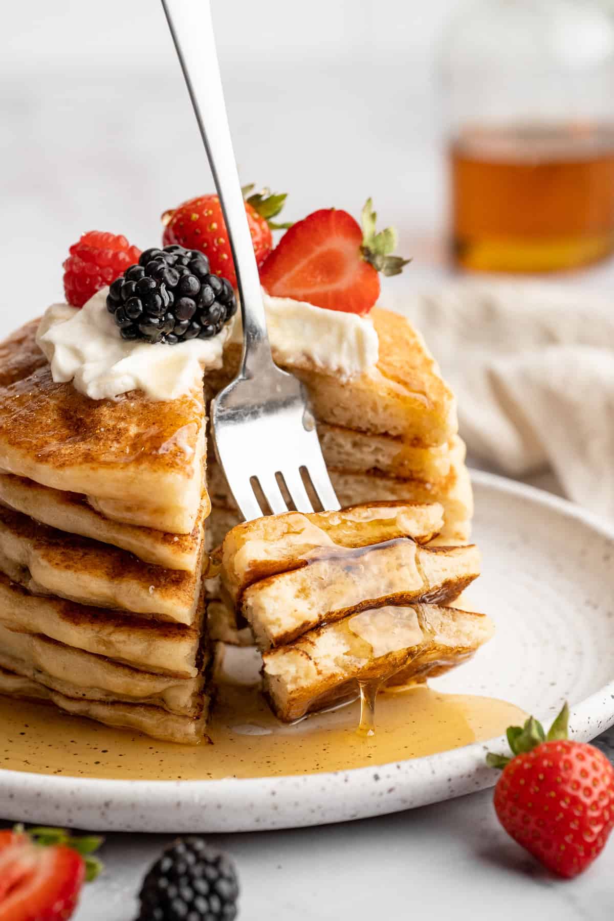 Easy to make and SO light and fluffy, these vegan cottage cheese pancakes are about to become your go-to, protein-packed breakfast. A fork diving into a stack of vegan cottage cheese pancakes.