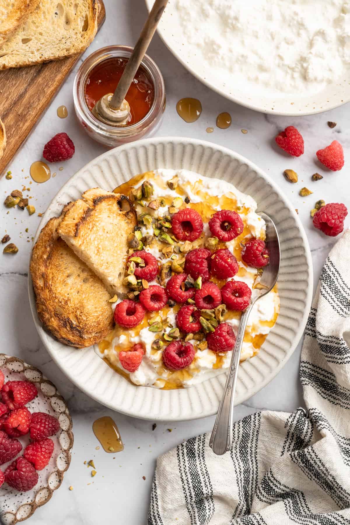 This vegan cottage cheese recipe marinates perfectly tender tofu "curds" in a savoury, tangy, salty sauce. It's a vegan staple you need! Vegan cottage cheese in a bowl with berries and nuts.