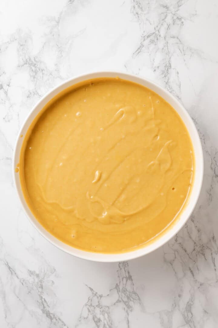 This vegan yellow cake is made of two layers of moist, tender, golden-yellow cake, filled and frosted with silky chocolate buttercream. Vegan yellow cake batter in a bowl.