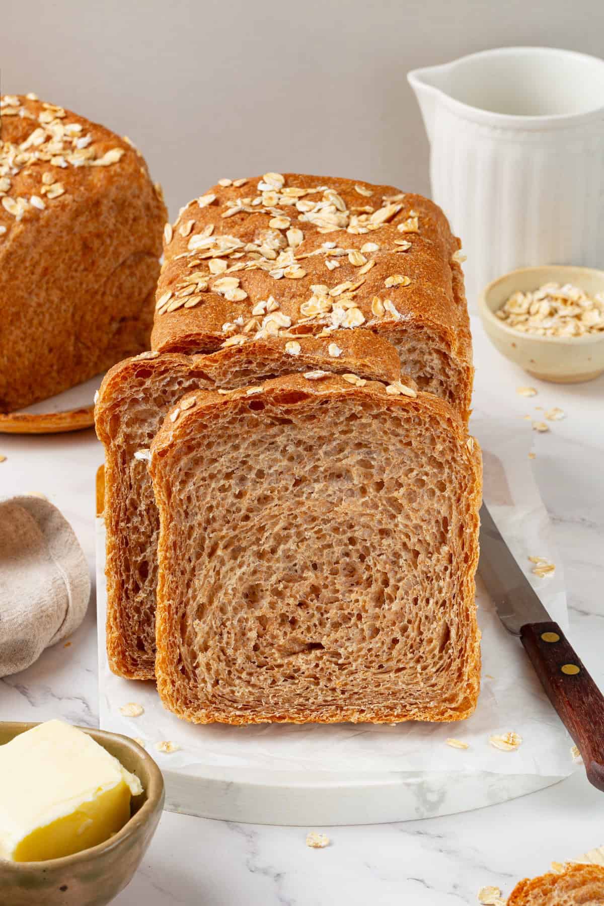 Looking for the perfect slice to build your PB&J or avocado toast on? This soft, tender whole grain sandwich bread is for you. Two slices of homemade whole grain sandwich bread leaning against a loaf.