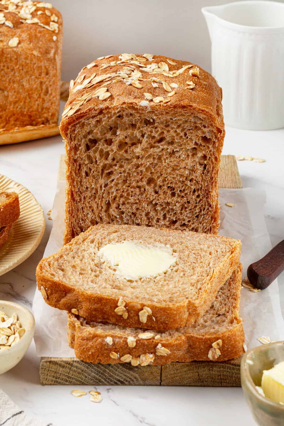Looking for the perfect slice to build your PB&J or avocado toast on? This soft, tender whole grain sandwich bread is for you. A loaf of whole grain sandwich bread with buttered slices cut from it.