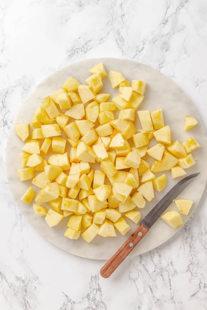 Apple butter should be the first on your autumn to-make list. Smooth and glossy, it's bursting with all the cozy spices of the season. Cubed apples on marble slab.
