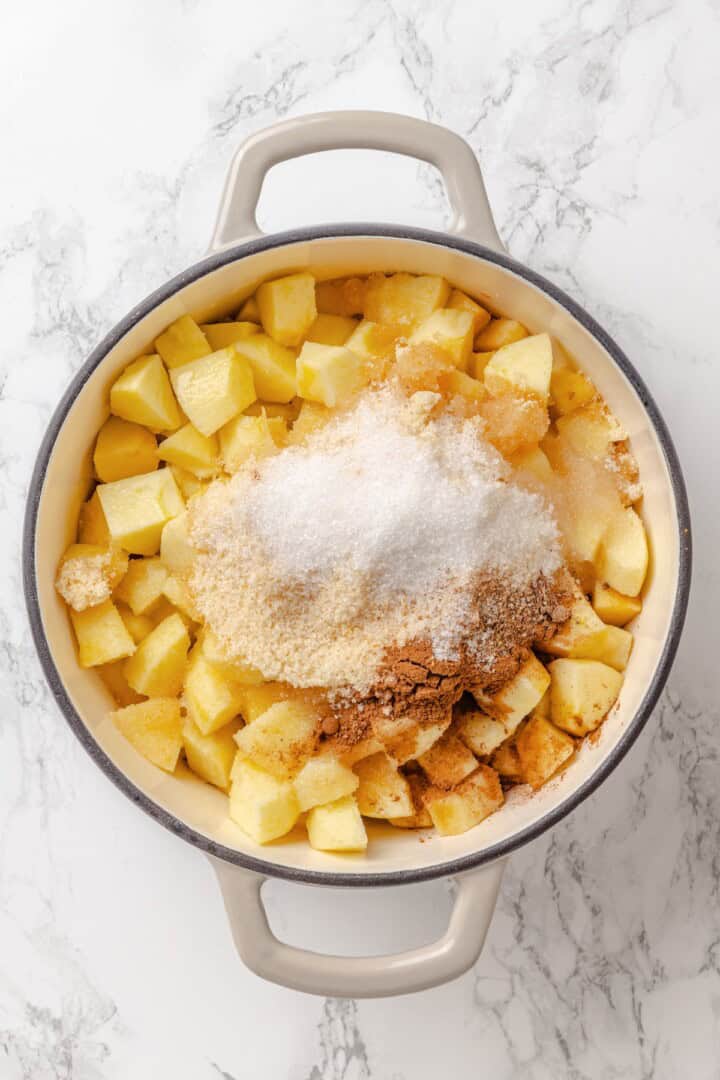 Apple butter should be the first on your autumn to-make list. Smooth and glossy, it's bursting with all the cozy spices of the season. Adding sugars, spices, and salt to cubed apples in a Dutch oven.