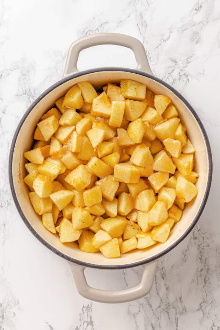 Apple butter should be the first on your autumn to-make list. Smooth and glossy, it's bursting with all the cozy spices of the season. Sugars, spices, and salt stirred into cubed apples in a Dutch oven.