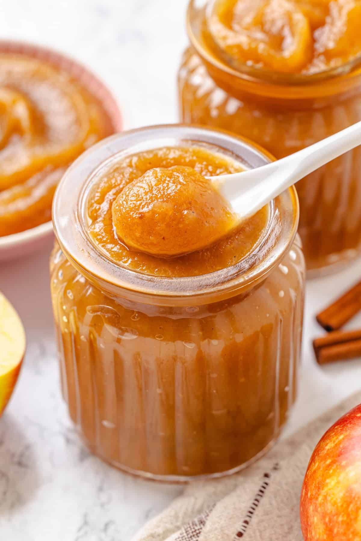 Apple butter should be the first on your autumn to-make list. Smooth and glossy, it's bursting with all the cozy spices of the season. A spoon holding a scoop of apple butter above a jar.