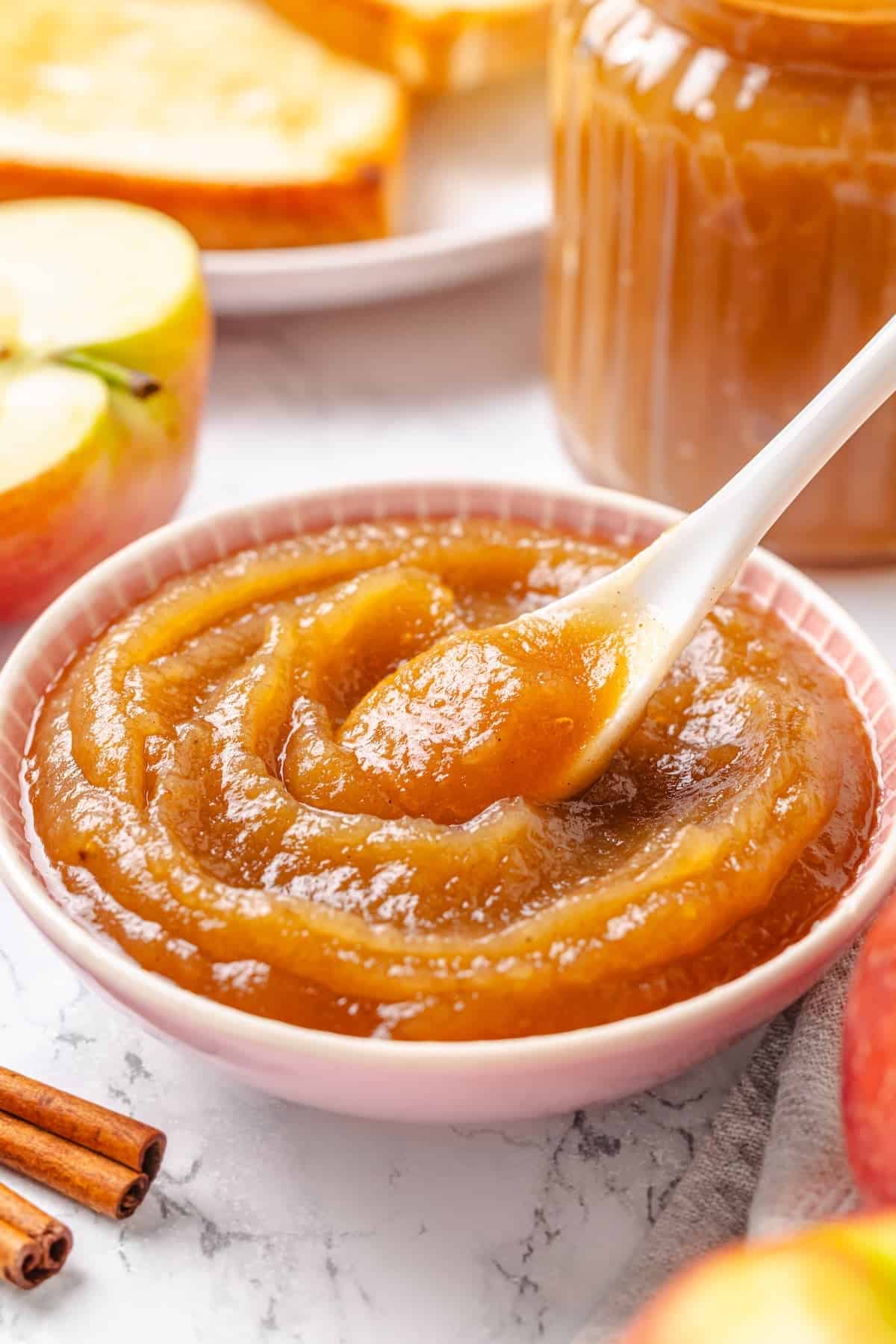 Apple butter should be the first on your autumn to-make list. Smooth and glossy, it's bursting with all the cozy spices of the season. Homemade apple butter in a bowl with a spoon.