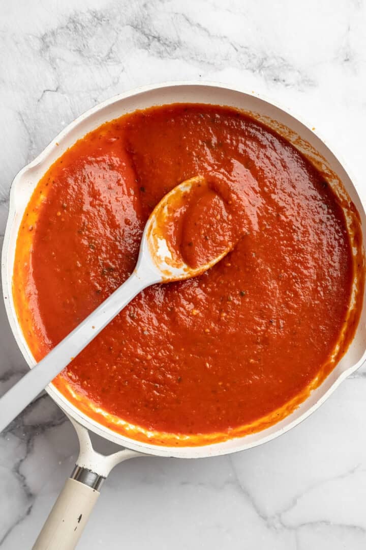 Vegan baked ziti, with its al dente noodles, savoury marinara sauce, and gooey cheese, married together bite after bite, is true comfort food. Warming marinara sauce in a pot.