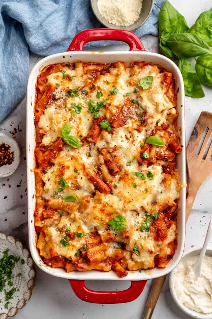 Vegan baked ziti, with its al dente noodles, savoury marinara sauce, and gooey cheese, married together bite after bite, is true comfort food. Overhead image of a baking dish full of cheesy vegan baked ziti.