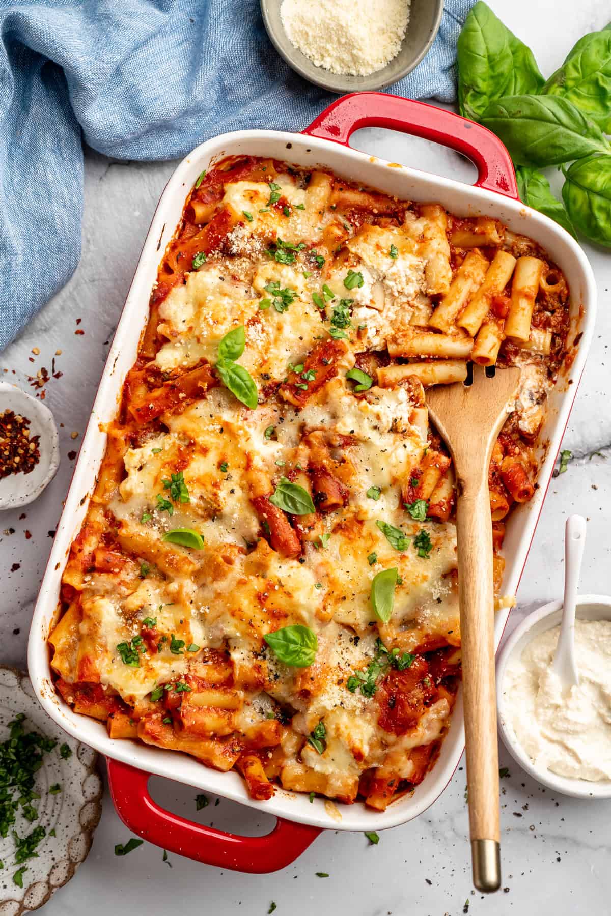 Vegan baked ziti, with its al dente noodles, savoury marinara sauce, and gooey cheese, married together bite after bite, is true comfort food. Overhead image of a baking dish full of vegan baked ziti.