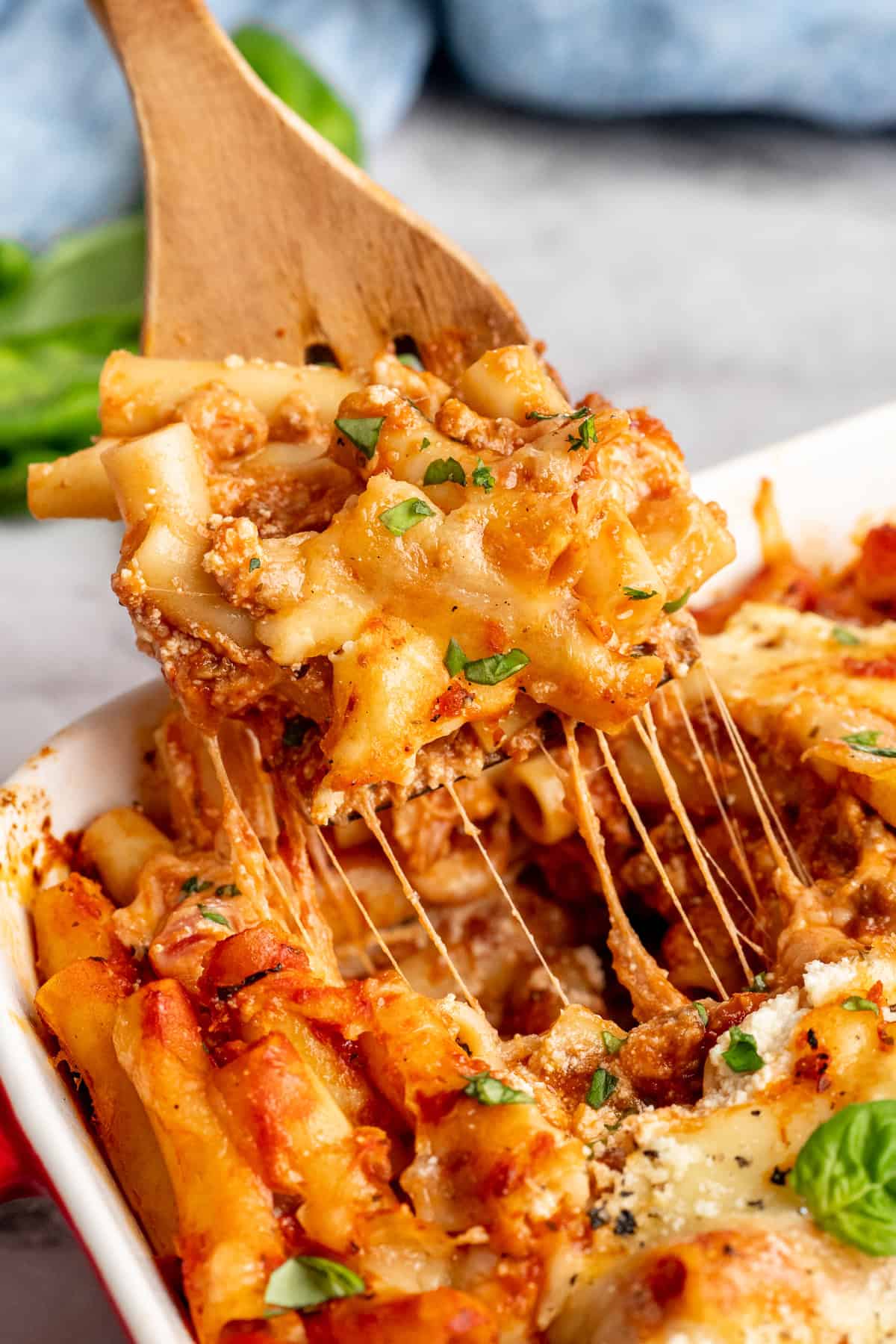 Vegan baked ziti, with its al dente noodles, savoury marinara sauce, and gooey cheese, married together bite after bite, is true comfort food. A serving spatula lifting some vegan baked ziti from the baking dish.