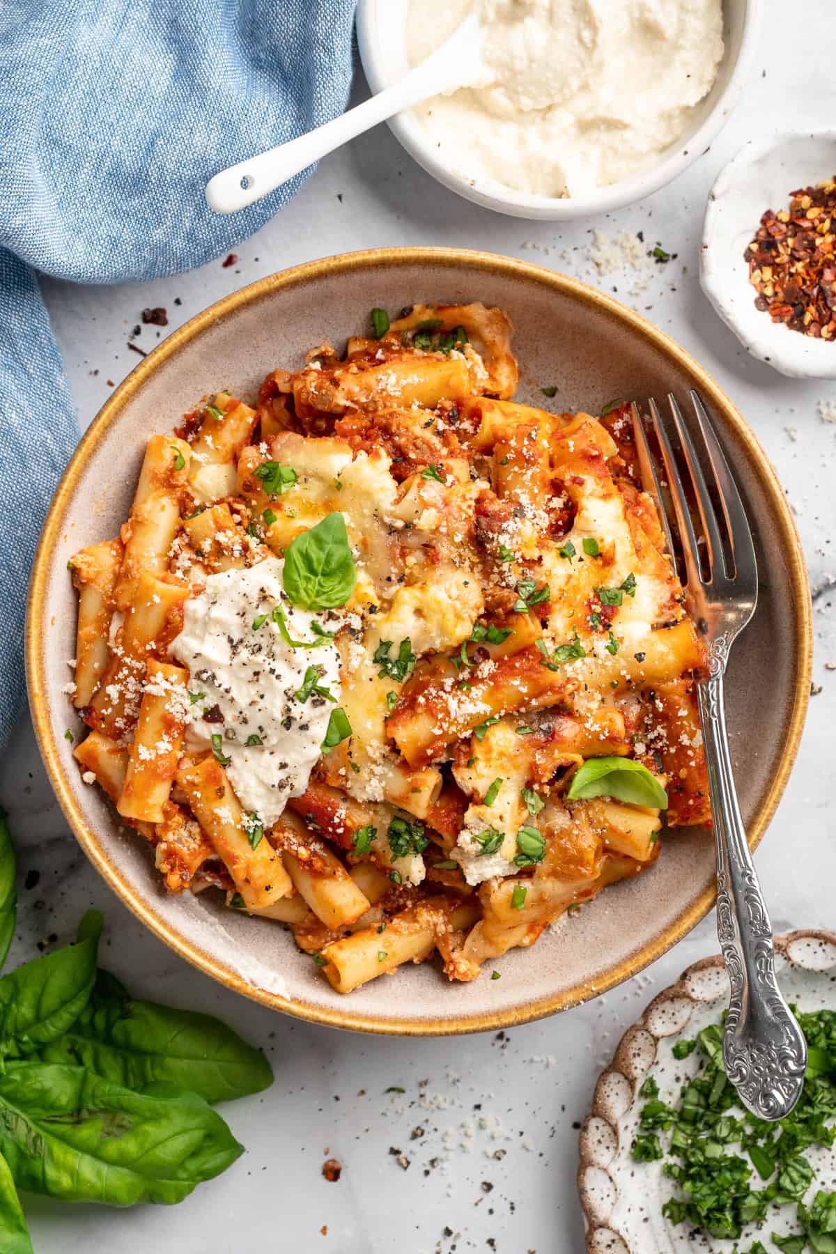 Vegan baked ziti, with its al dente noodles, savoury marinara sauce, and gooey cheese, married together bite after bite, is true comfort food. Overhead image of a bowl of vegan baked ziti.